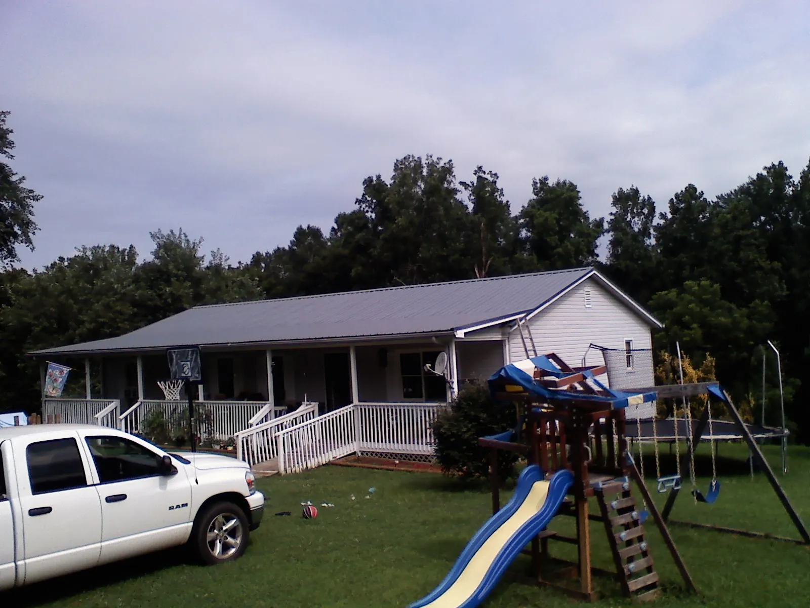 Dark metal roof on a country home with a full length front porch in Newport